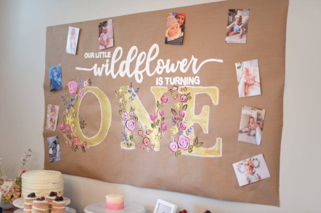 "Our Little Wildflower is turning one!" banner at wildflower first birthday theme party.